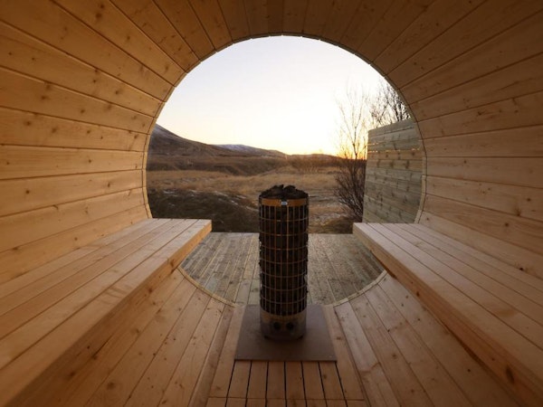 An idyllic countryside view looking out from the outdoor wooden sauna at Deluxe Lodge in South Iceland.
