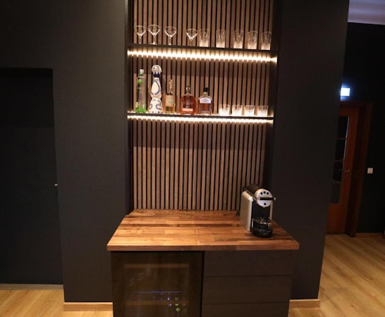 A mini bar area at Deluxe Lodge with an espresso machine, alcohol, and glasses.
