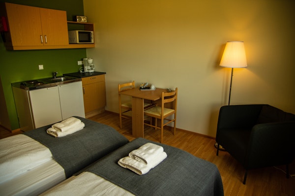 A spacious and well-appointed room at Fljotsdalsgrund, featuring twin beds and a kitchenette for a comfortable stay.