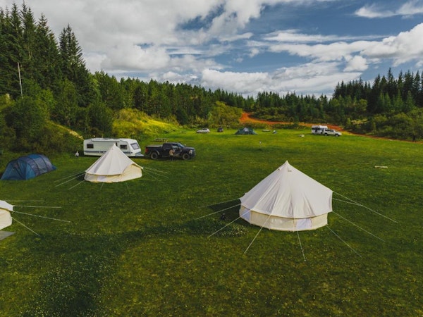 Two of the glamping tents at the Golden Circle Tents Glamping Experience with 4x4 vehicles and caravans in the background.