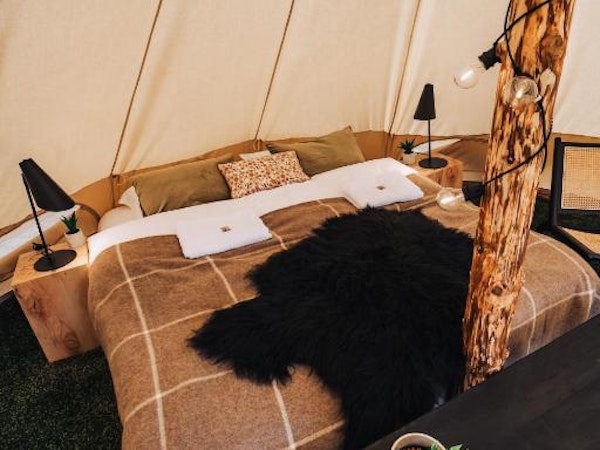 One of the double beds at the Golden Circle Tents Glamping Experience with a fluffy black blanket on top of it.
