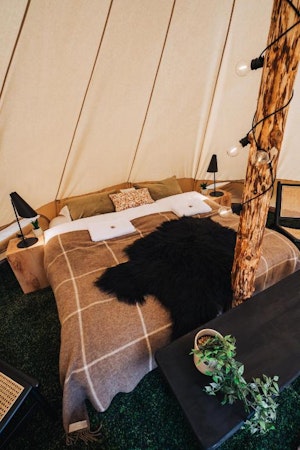 One of the double beds at the Golden Circle Tents Glamping Experience with a fluffy black blanket on top of it.