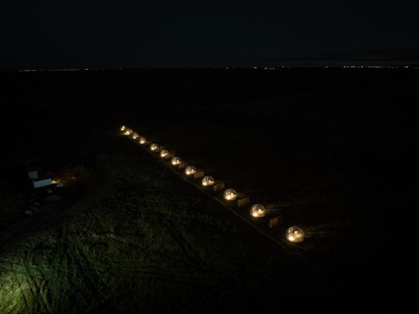 The Aurora Igloo site from above, showing a line of pods lit up in the dark.