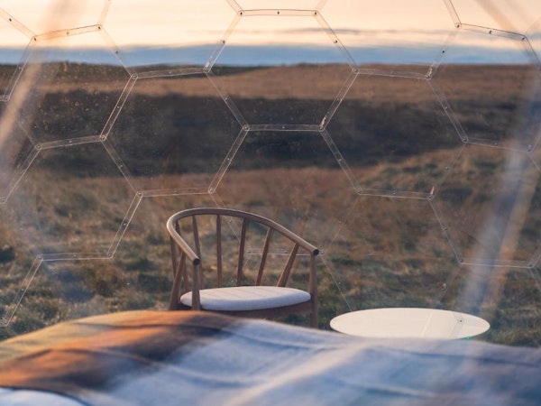A close up of a chair inside an Aurora Igloo and the view outside.