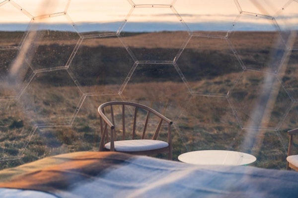 A close up of a chair inside an Aurora Igloo and the view outside.