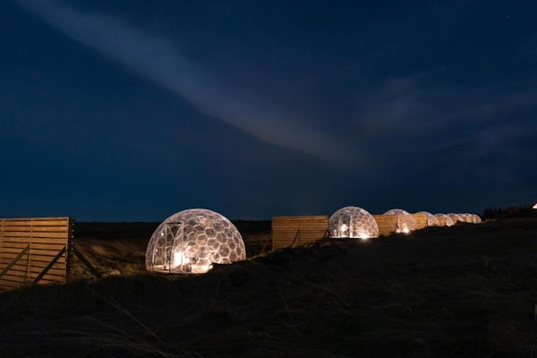 A row of four Aurora Igloos lit up in the dark.