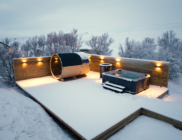The elegant outdoor spa area at Deluxe Lodge, complete with a sauna, jacuzzi, and cold tub, covered in a blanket of snow.