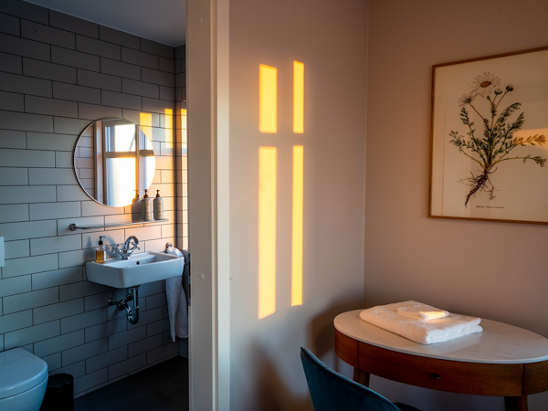 A view of a desk and chair in a room and a private bathroom at Soti Lodge.
