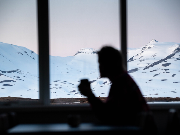 A silhouette of a person in the dining room at Soti Lodge looking across a snow-covered landscape.