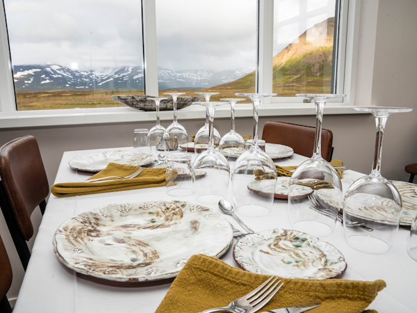 A dining room table set with cutlery and wine glasses boasts stunning mountain views at Soti Lodge.