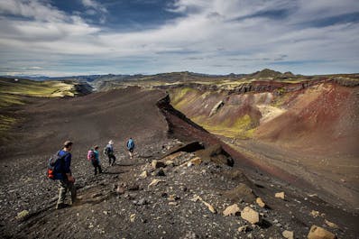 A hiking group walks along the dramatic mountainous landscape of the Highlands in Iceland.