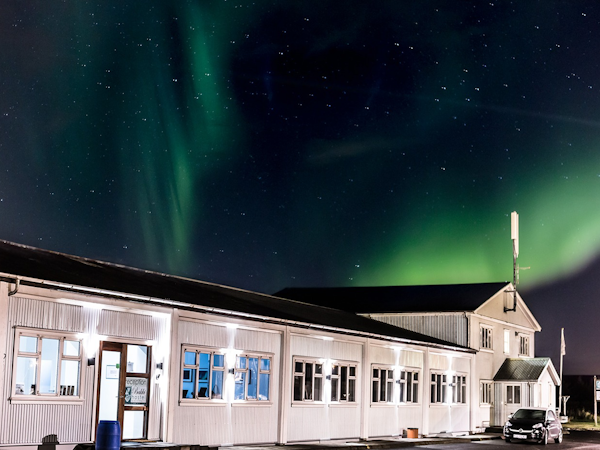 Behold the enchanting spectacle of the hostel under the mesmerizing glow of the northern lights.