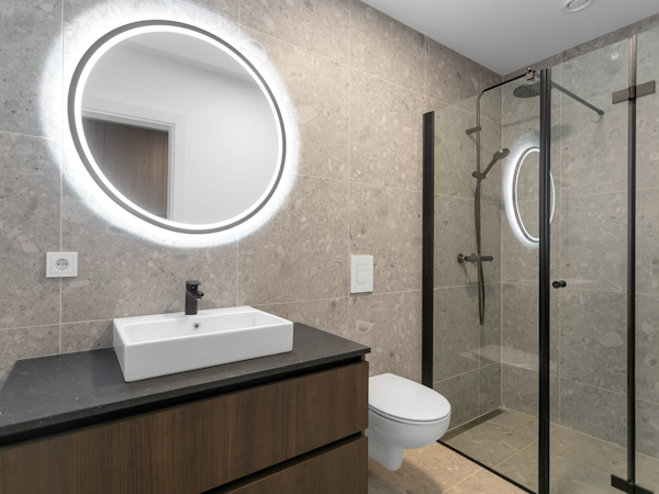 Unwind in style in the sleek and modern minimalist bathroom, where the lighted mirror adds a touch of sophistication to your Hle