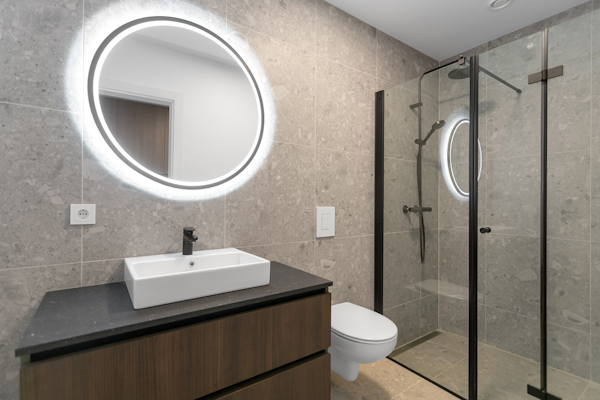 Unwind in style in the sleek and modern minimalist bathroom, where the lighted mirror adds a touch of sophistication to your Hle