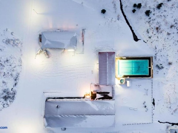An overhead view of Soti Lodge and its surrounding facilities, including a swimming pool, amid a snow-covered landscape.
