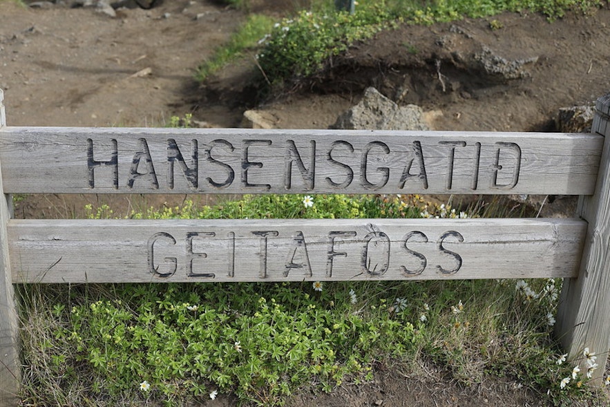 A wooden sign saying "Hansensgatid" and "Geitafoss."