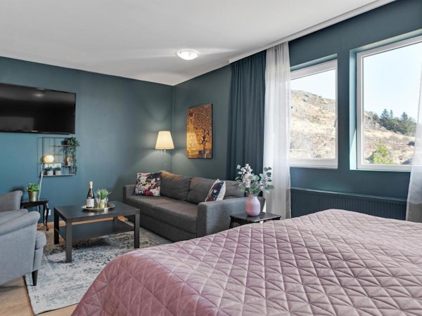 A spacious and stylish room at Hotel Kvika with a sofa, flatscreen television, and comfortable bed.