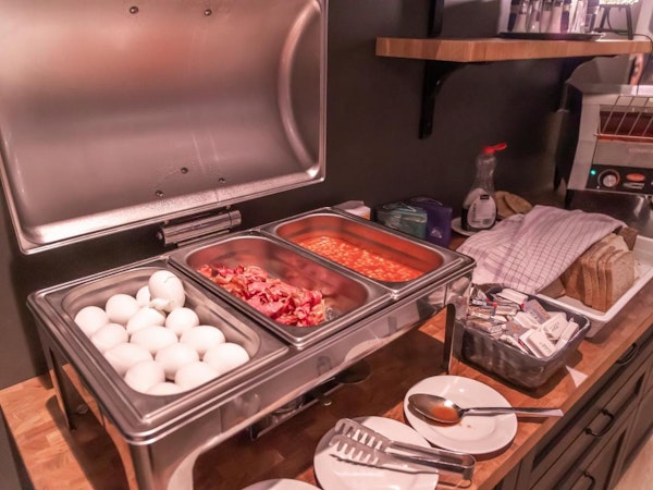 A selection of warm foods, including boiled eggs, bacon, and baked beans at Hotel Kvika.