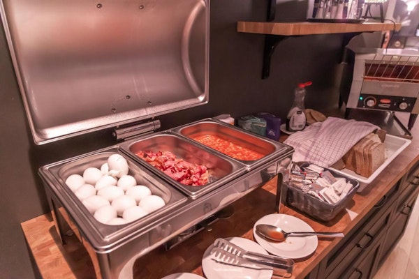 A selection of warm foods, including boiled eggs, bacon, and baked beans at Hotel Kvika.
