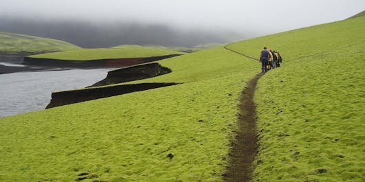 Hikers wander along a trail amid a stunningly green landscape next to the Skafta river in the Icelandic Highlands.
