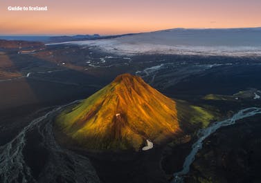 The Maelifell volcano contrasts stunningly with its surroundings at sunset.