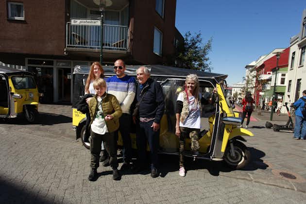 A group of people stand in front of their tuk-tuk for a photo during a tour around Reykjavik.