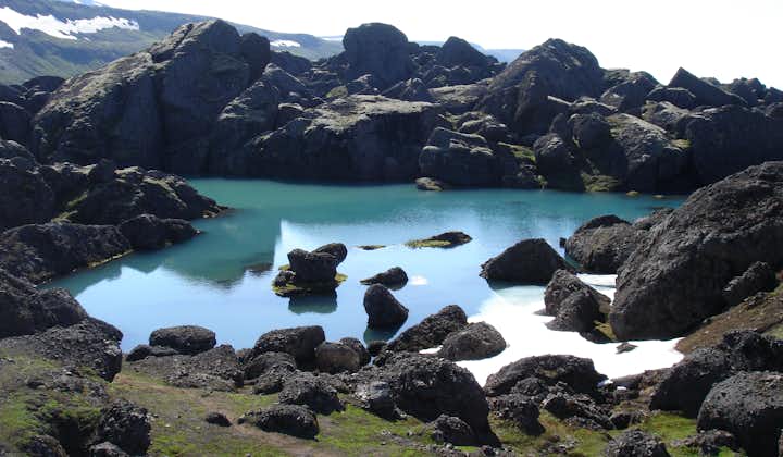 A lake in Stórurð surrounded by black boulders