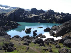 A lake in Stórurð surrounded by black boulders
