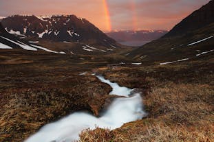 Un arcobaleno gemello si inarca su un fiordo, in un giorno di sole e splendore dell'estate islandese.