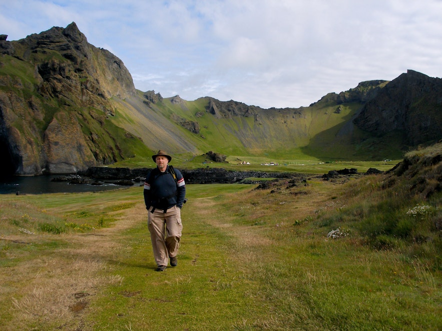 A traveler posing for a photo on the green valley of Herjolfsdalur.