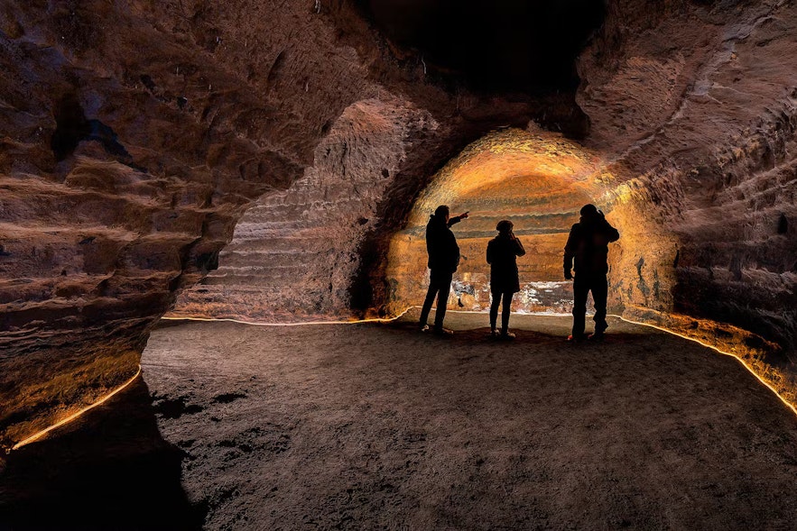Three people stand in one of the caves at Hella.