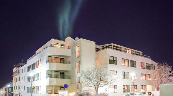 The aurora borealis shines above Sunna Guesthouse in winter.