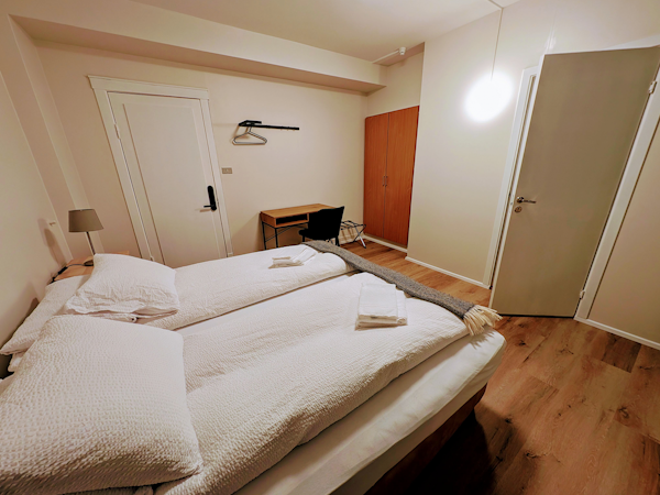 A view inside a room at the Stykkisholmur Inn with a double bed, a desk, and a closet.