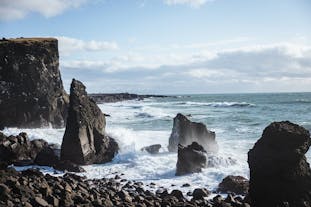 Sea stacks in the Atlantic Ocean off the Icelandic coast as waves come crashing onto the shore.
