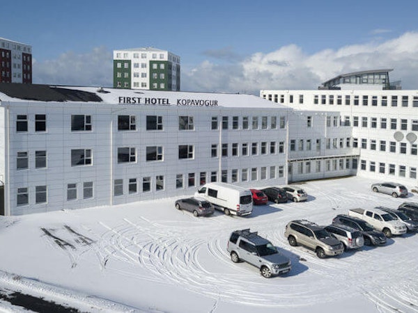 Cars parked outside 201 Hotel in Kopavogur on a snow-covered landscape.