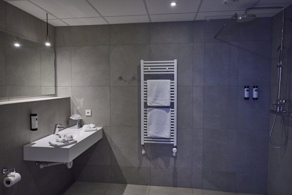 A bathroom with a heated towel rail and towels at Hotel Vesturland in Borgarnes.