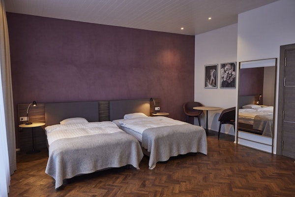 A spacious room with two beds and a sitting area at Hotel Vesturland.