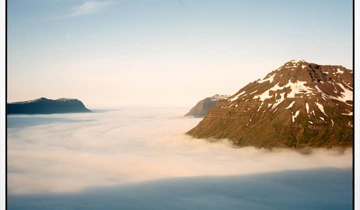 A sunset view of Mount Bjolfur on the Seydisfjordur fjord looking down on a soft blanket of cloud.