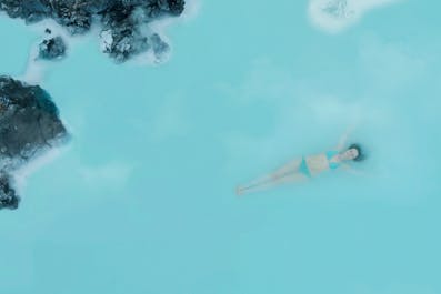 Een vrouw drijft in het blauwe water van de geothermische spa Blue Lagoon.