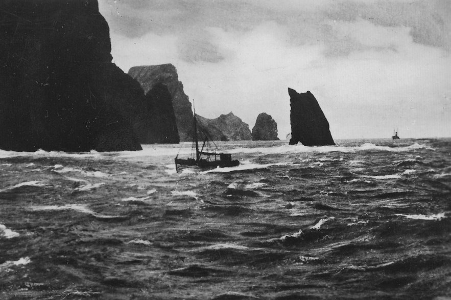 一张10x15的旧烟卡，上面印有冰岛恶劣天气下的一艘渔船。