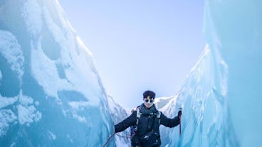 A person walks through a blue ice tunnel on a glacier hiking tour in the Vatnajokull National Park.