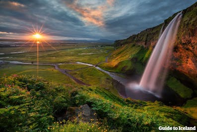 See an unmatched view of South Iceland's lowlands from behind Seljalandsfoss waterfall.