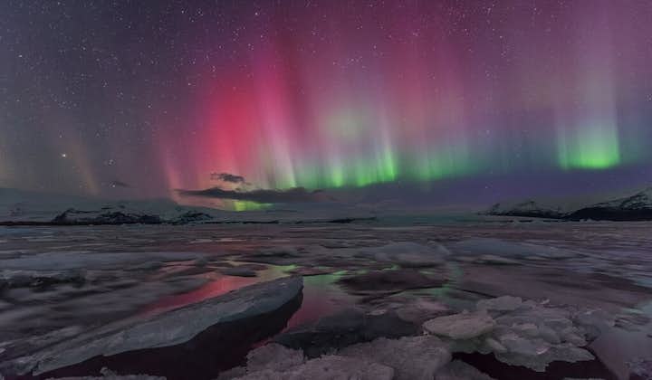 The Northern Lights fill the sky and dye the surroundings their colours, particularly over Jökulsárlón glacier lagoon.