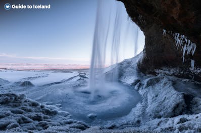 Seljalandsfoss waterfall looks picture-perfect surrounded by a snow-covered winter landscape.