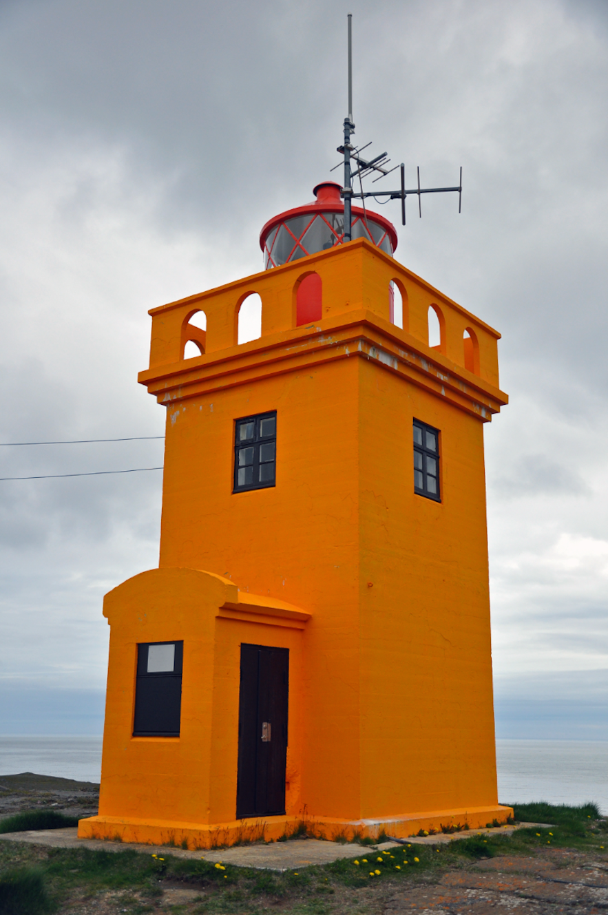 An orange lighthouse on the coast of Northeast Iceland.