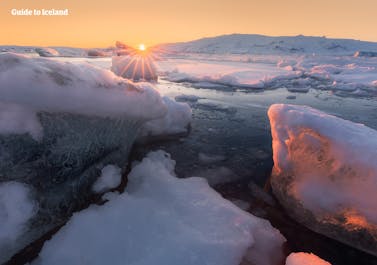 The sun sets at Jokulsarlon glacier lagoon, lighting the sky in a beautiful shade of orange, the perfect contrast to the landscape below.