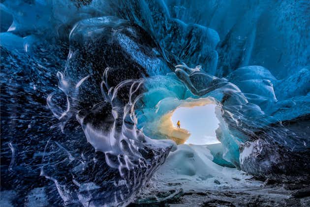 A bright winter's day is visible through the entrance of one of Vatnajökull's crystal blue ice caves.