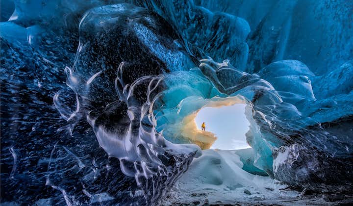 A bright winter's day is visible through the entrance of one of Vatnajökull's crystal blue ice caves.