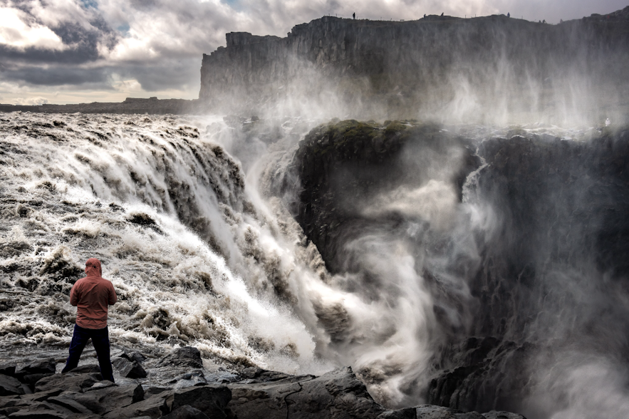 A man stands overlooking Dettifoss waterfall, one of the waterfalls created by Jokulsargljufur river canyon.