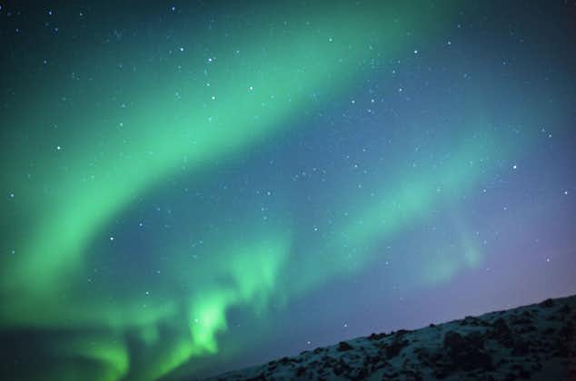 An ethereal sky of infinite stars and descending aurora lights in west Iceland's winter.